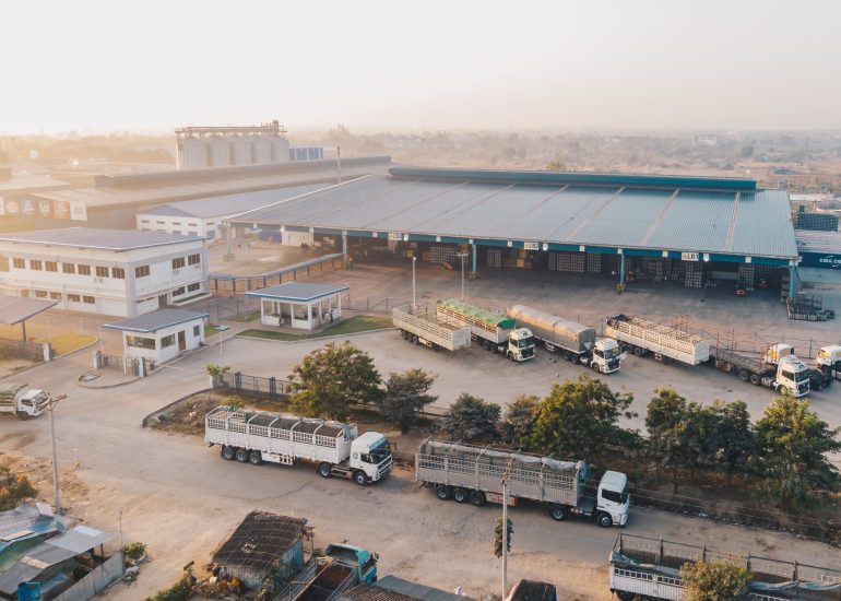 An aerial shot of factory trucks parked near the warehouse at daytime
